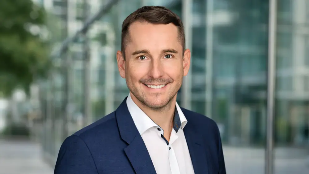 Businessportrait eines Mannes im Freien vor unscharfem Bürogebäude