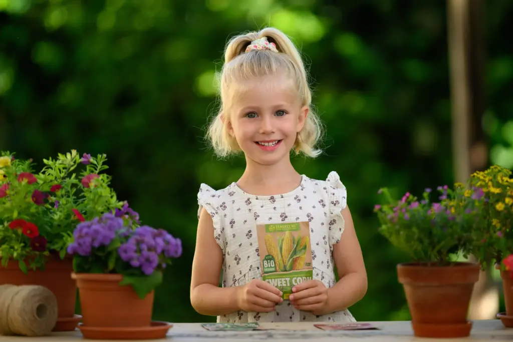 Mädchen mit Samentütchen am Pflanztisch beim Kindergarten-Fototag